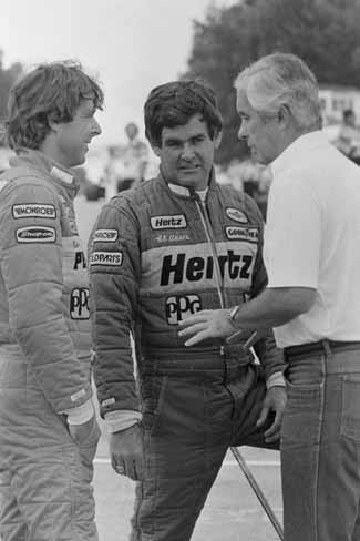 Racing legends Al Unser (center) and Rick Mears (left) listen to Roger Penske